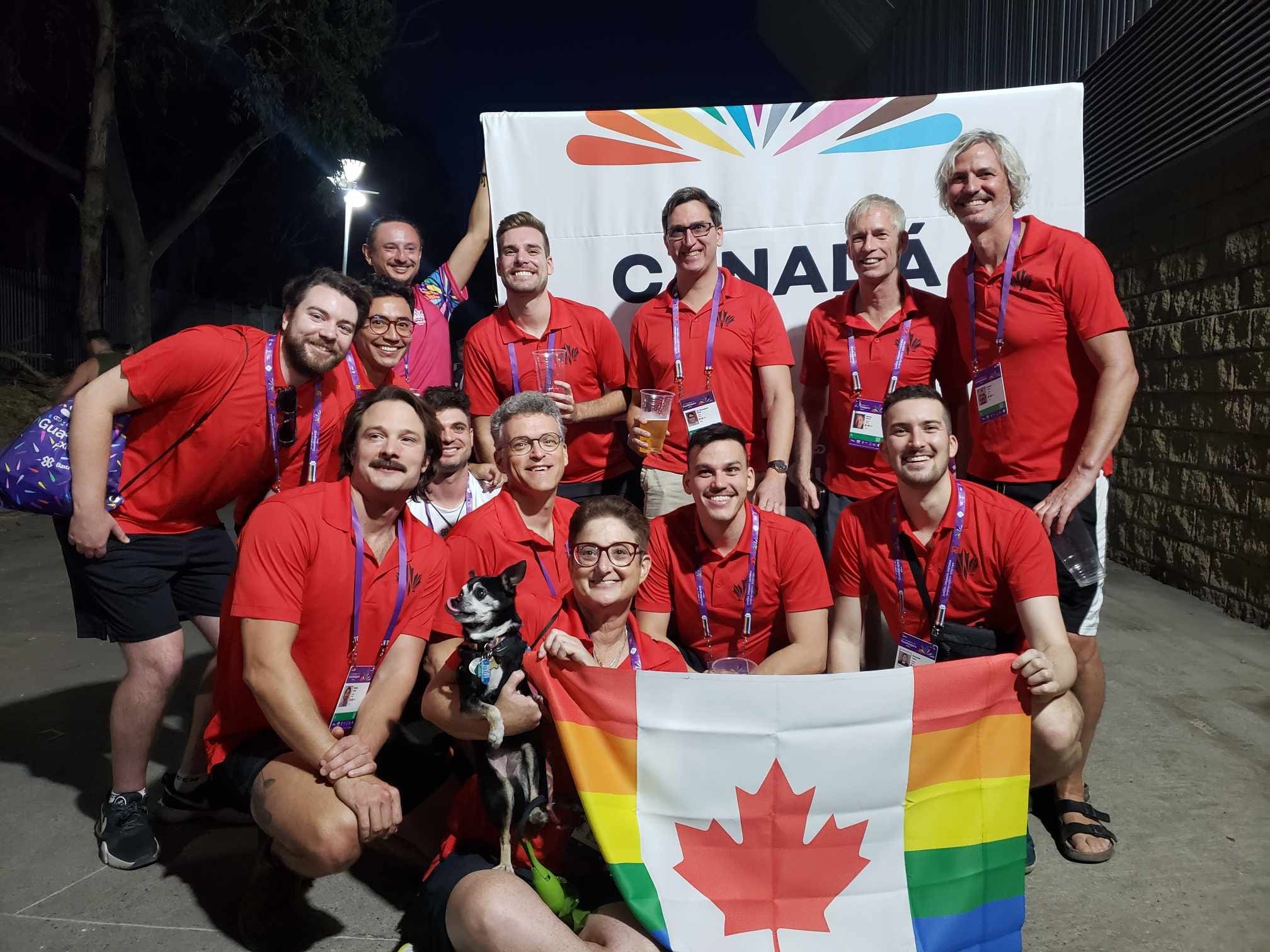 Members of the Rideau Speedeaus gather for the Gay Games; they carry a rainbow Canada flag and wear red polo shirts.